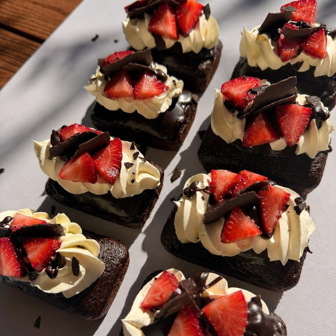 Small desserts with chocolate, cream, and strawberries on a white plate.