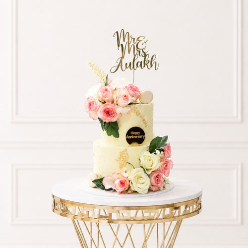 Decorative cake with flowers and 'Happy Anniversary' topper on a marble table.