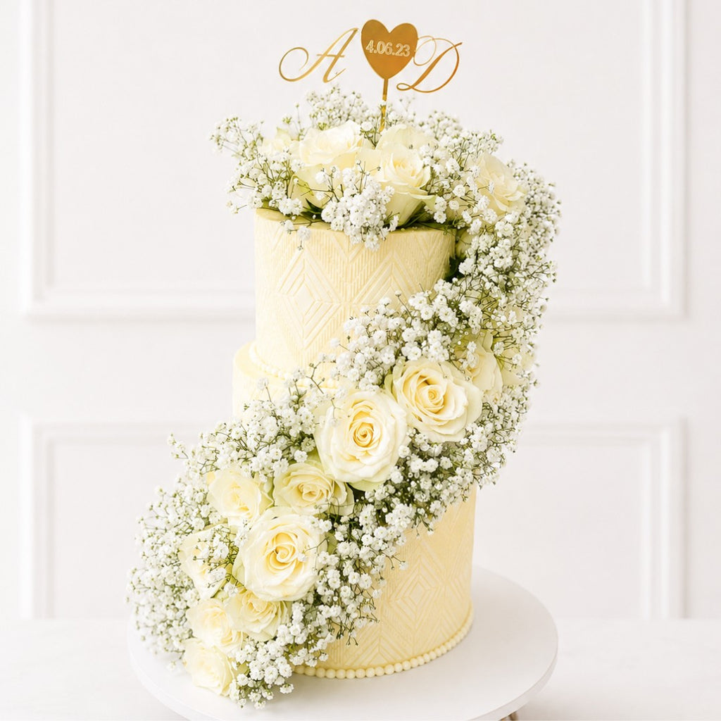 Two-tiered wedding cake decorated with white flowers on a white background