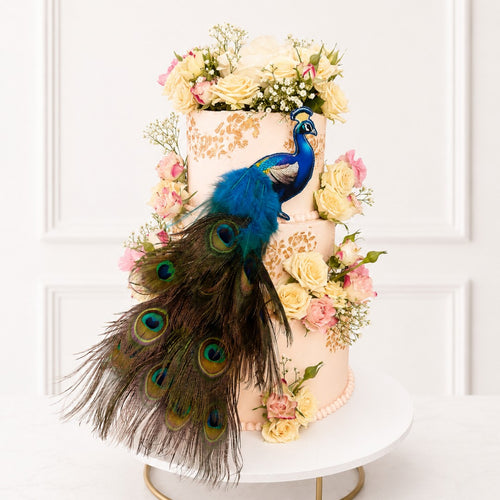 Decorative cake with peacock feathers and flowers on a white background