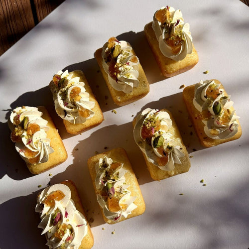 Small square pastries with cream and fruit toppings arranged on a light surface.
