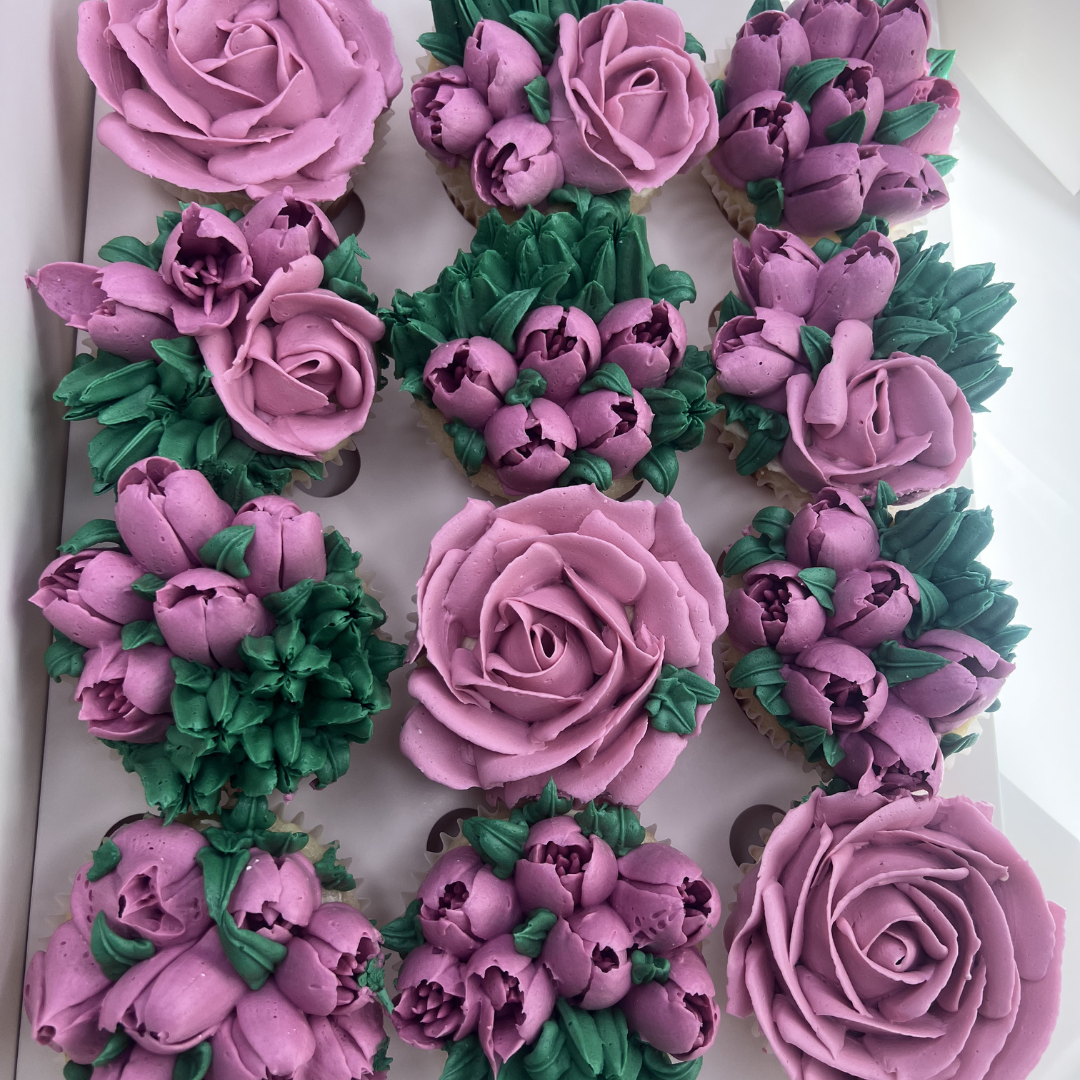 Photo of twelve beautiful flower themed cupcakes covered in buttercream
